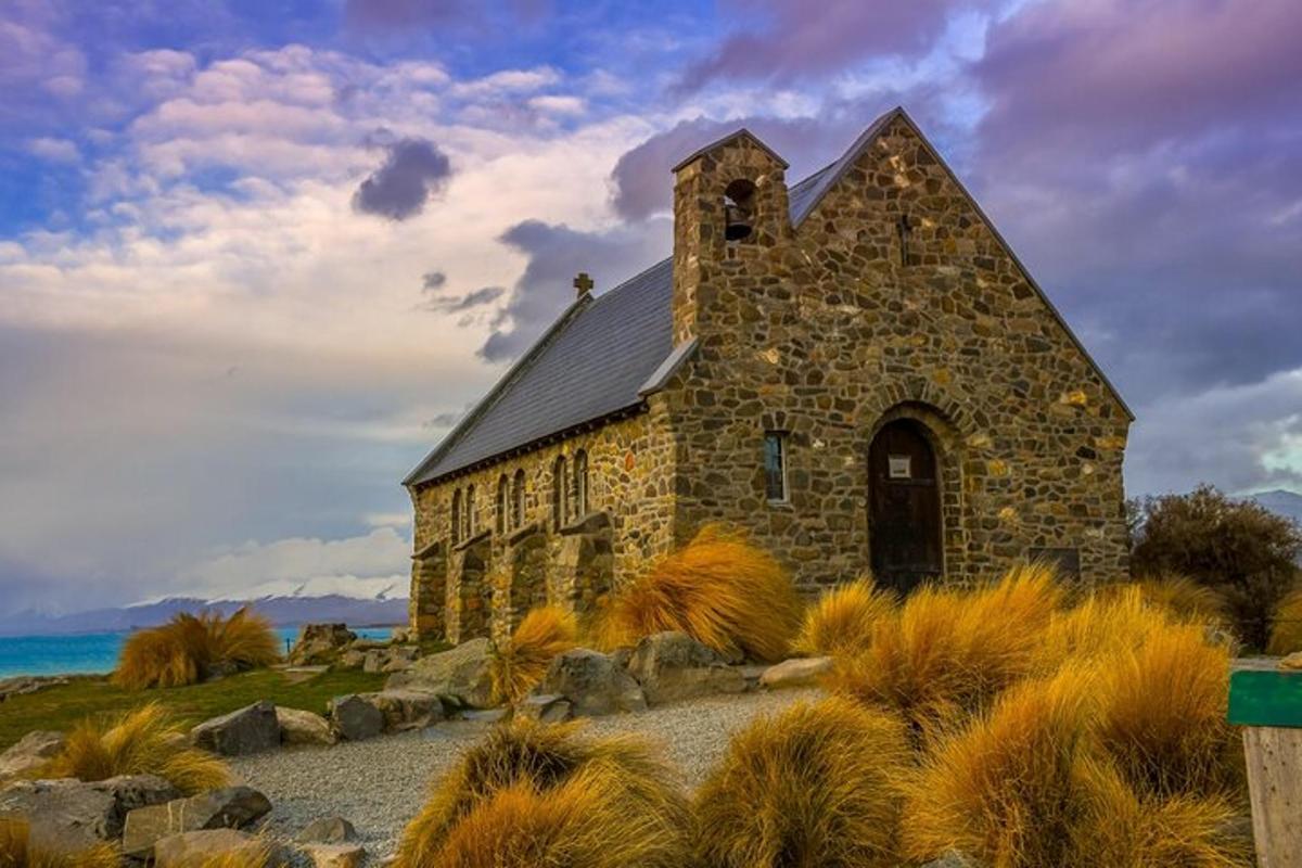an old stone church in a field with grass