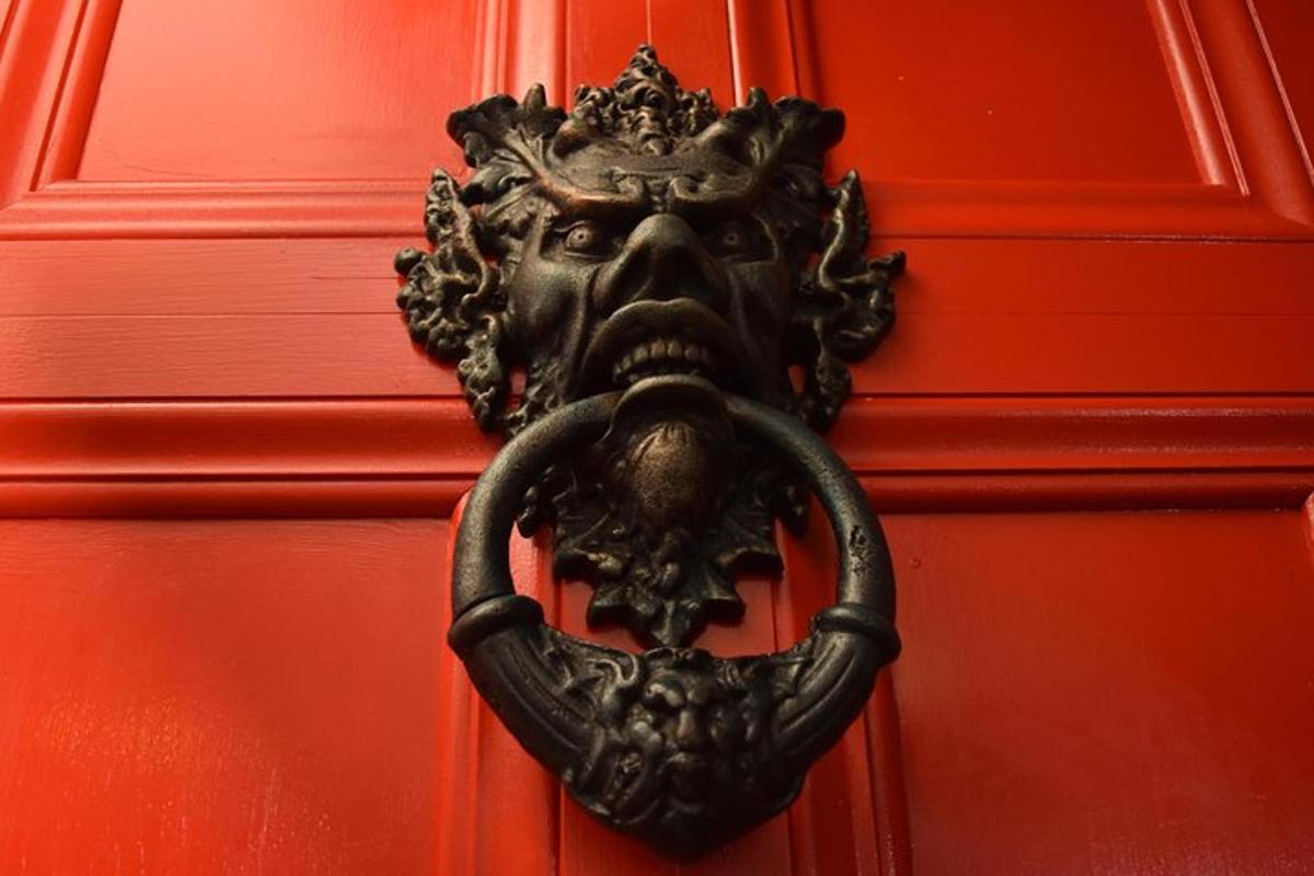 un batacchio di porta raffigurante un volto su una porta rossa