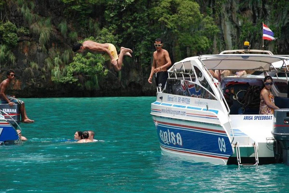a group of people jumping off a boat in the water
