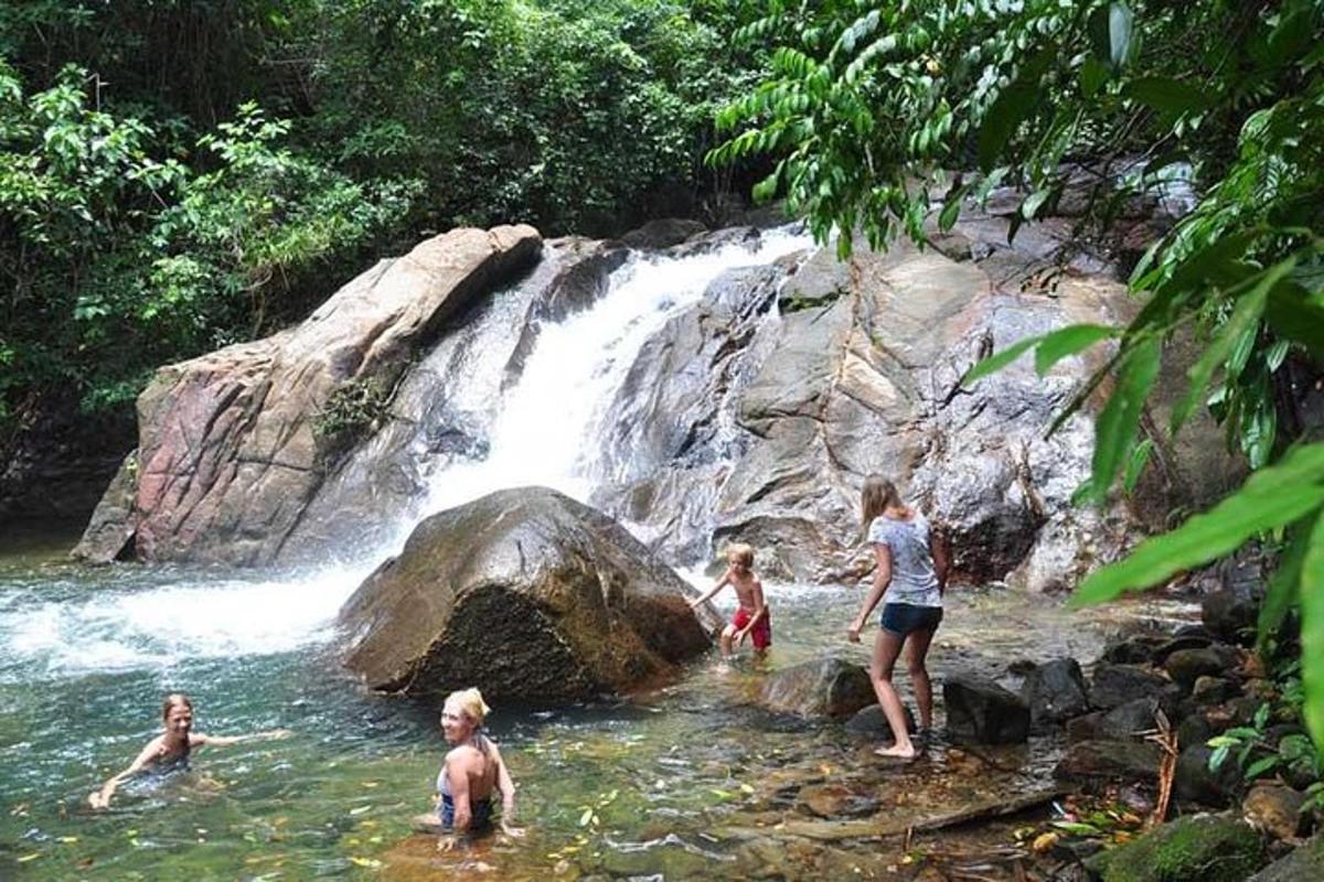 a group of people in the water near a waterfall