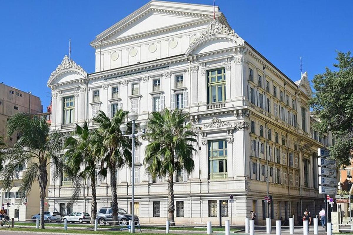 a large white building with palm trees in front of it