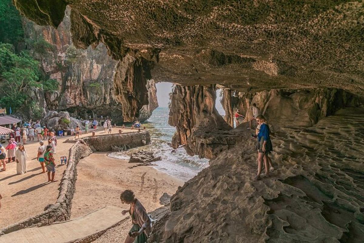 Una pintura de una playa con gente parada en las rocas.