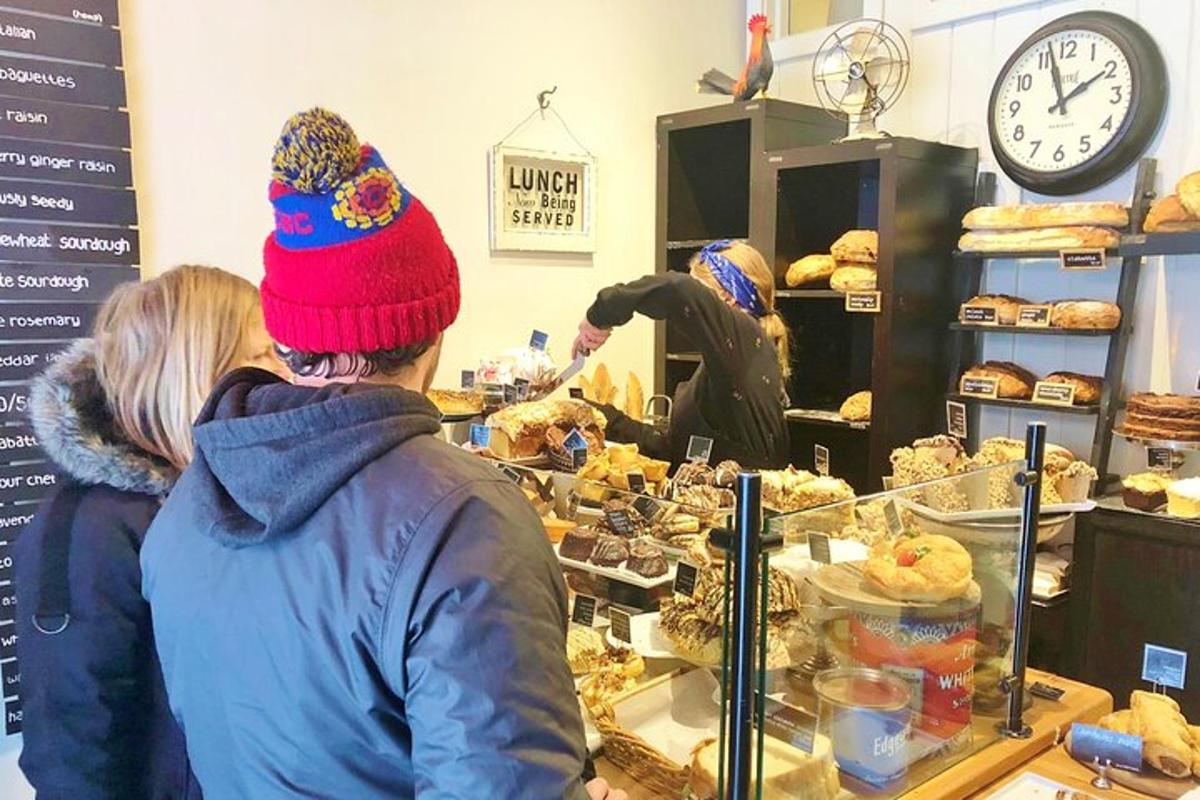 două persoane care stau la tejgheaua unei brutării uitându-se la produse de patiserie