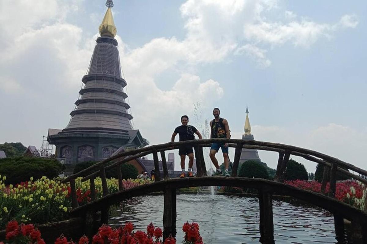 two people sitting on a bridge over a pond in front of a temple