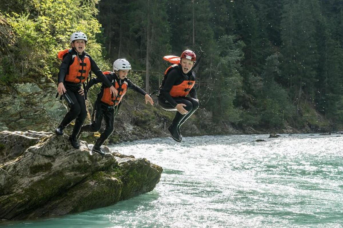 three people jumping off a rock in a river