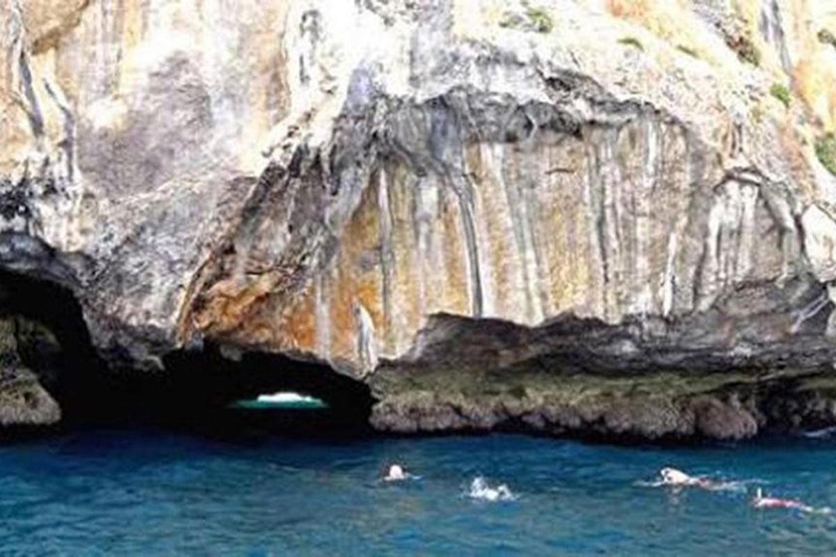 Δύο άνθρωποι κολυμπούν στο νερό μπροστά σε μια σπηλιά