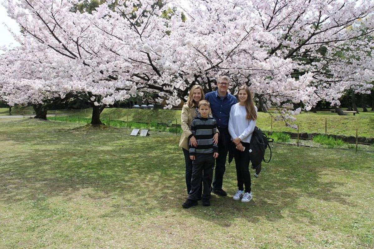 en familj som står framför ett träd med blommor