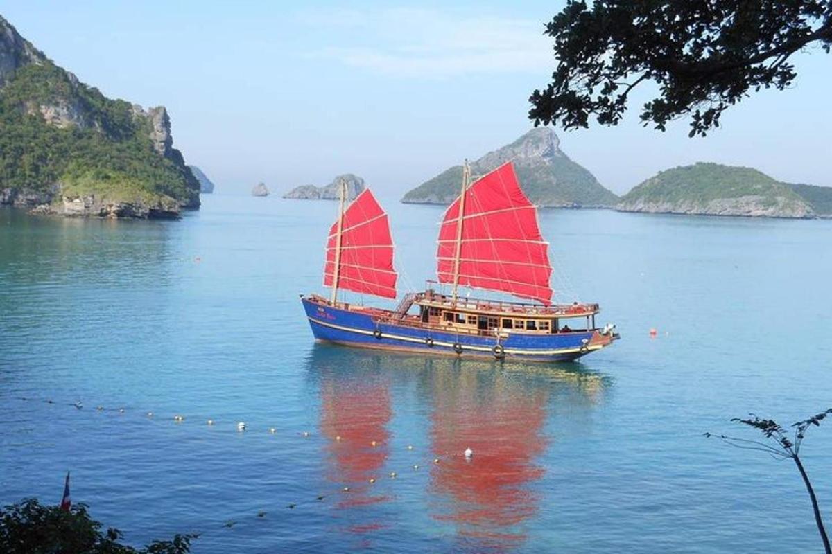 một chiếc thuyền có cánh buồm đỏ trên mặt nước