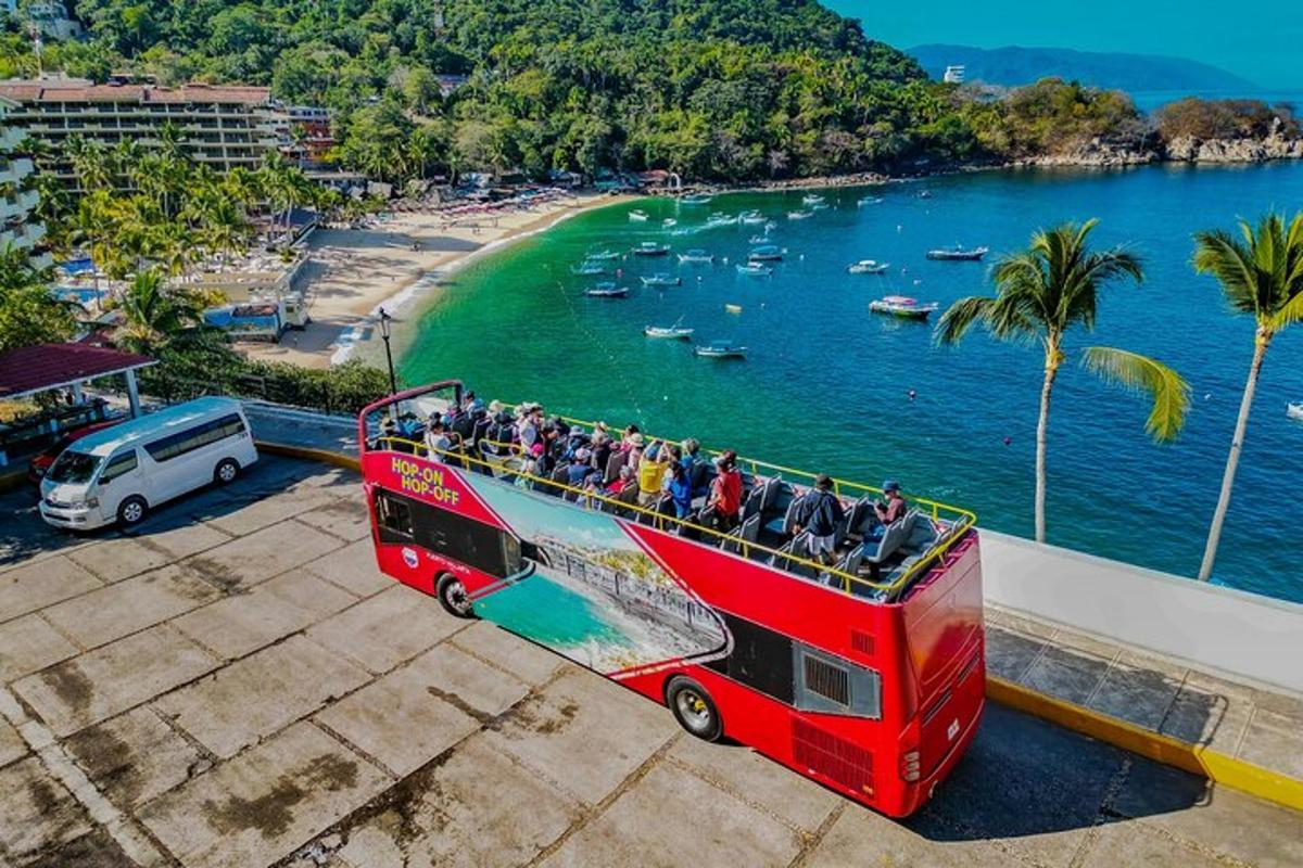 a red double decker bus parked next to a beach