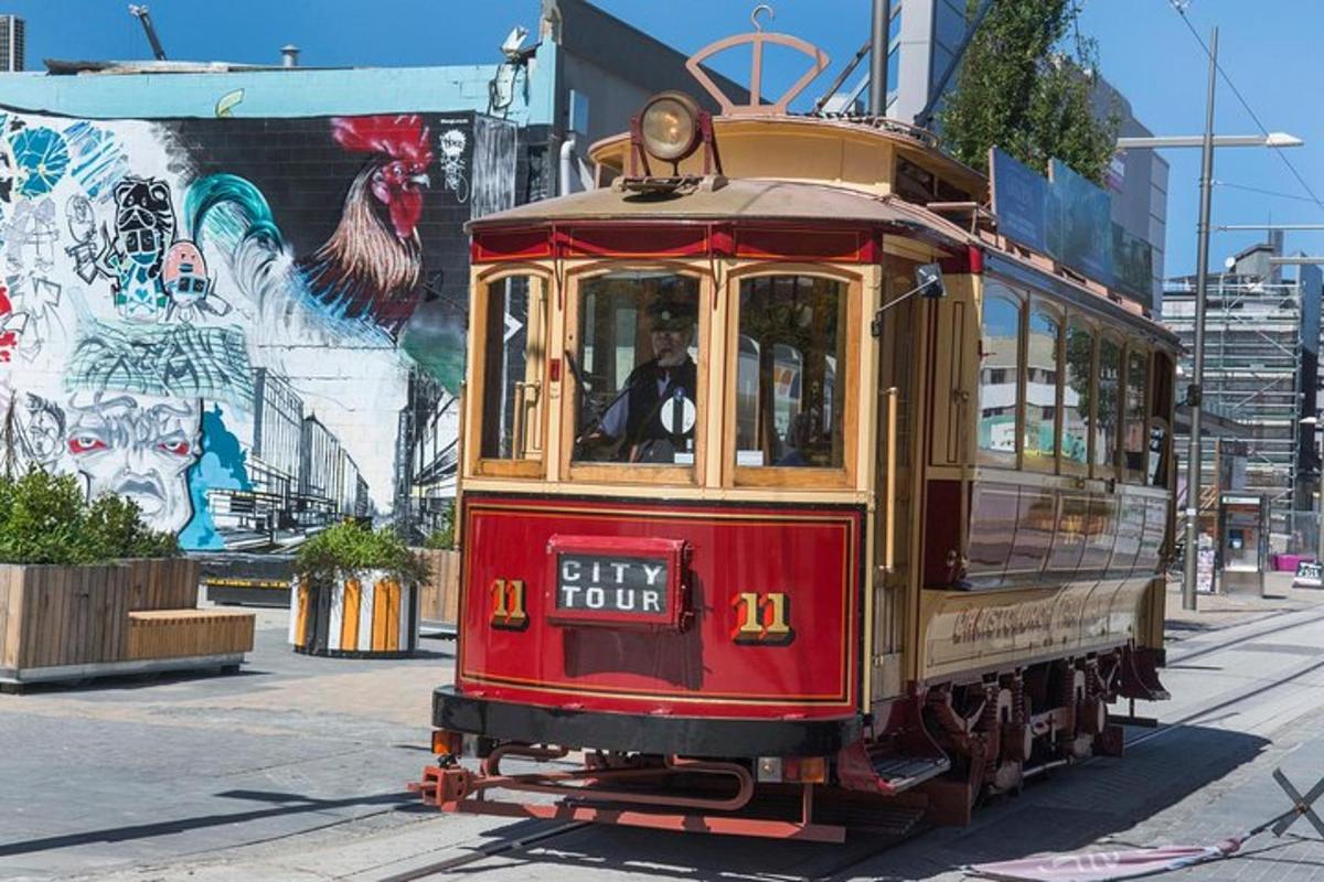 a red trolley car on a street with a mural