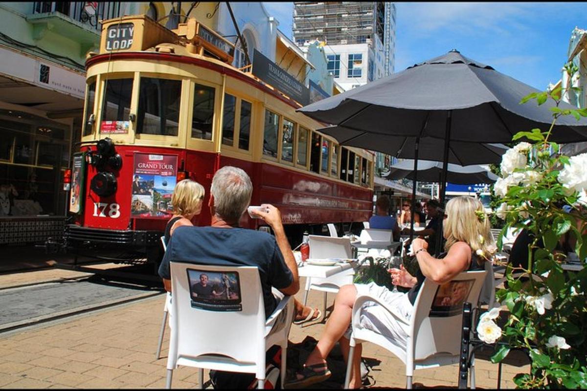 a group of people sitting at tables in front of a tram