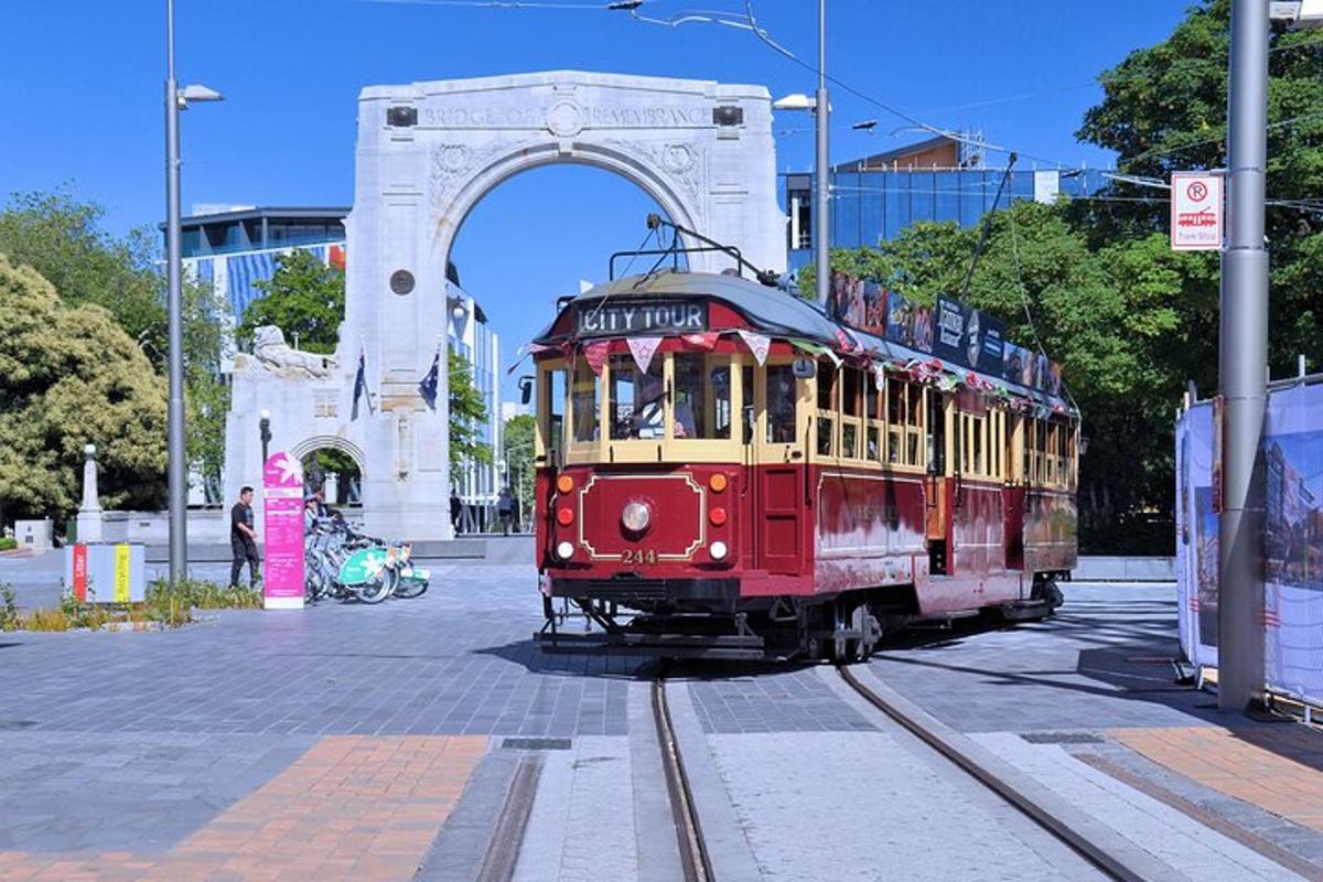 a red and yellow trolley on tracks in front of an arch