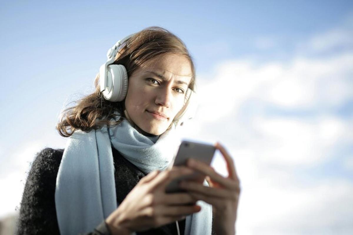 un uomo che indossa le cuffie e guarda un cellulare