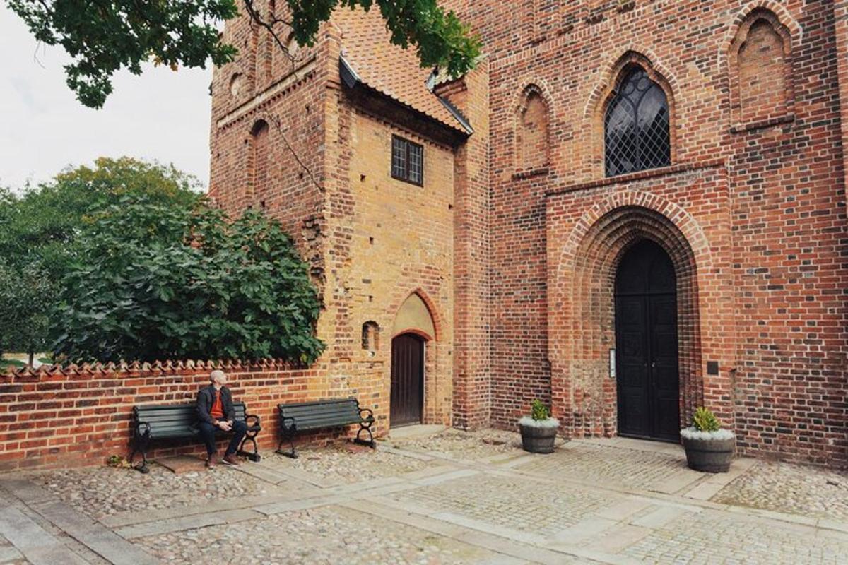 a man sitting on a bench in front of a brick building