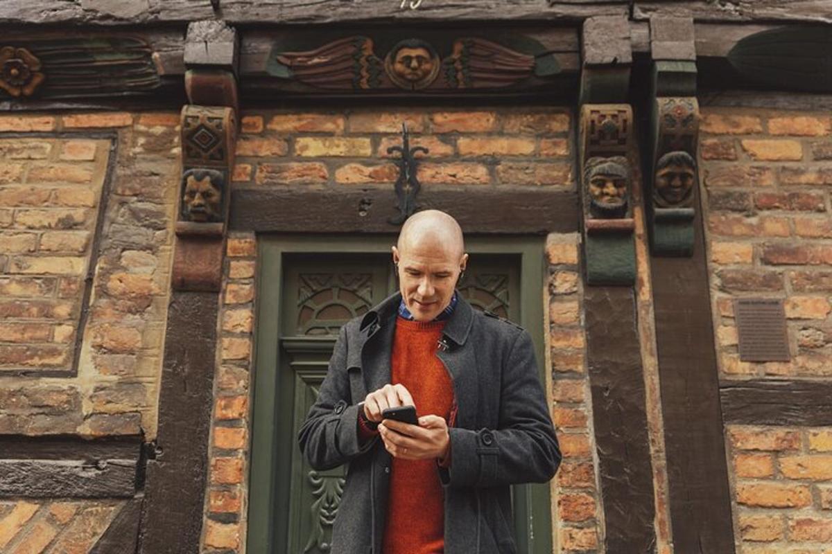 a man standing in front of a building looking at his cell phone