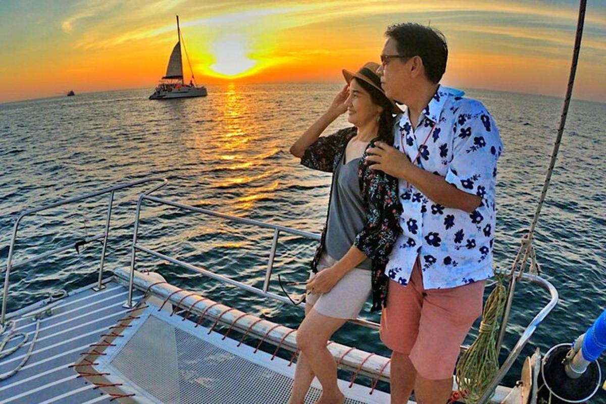un uomo e una donna in piedi su una barca al tramonto