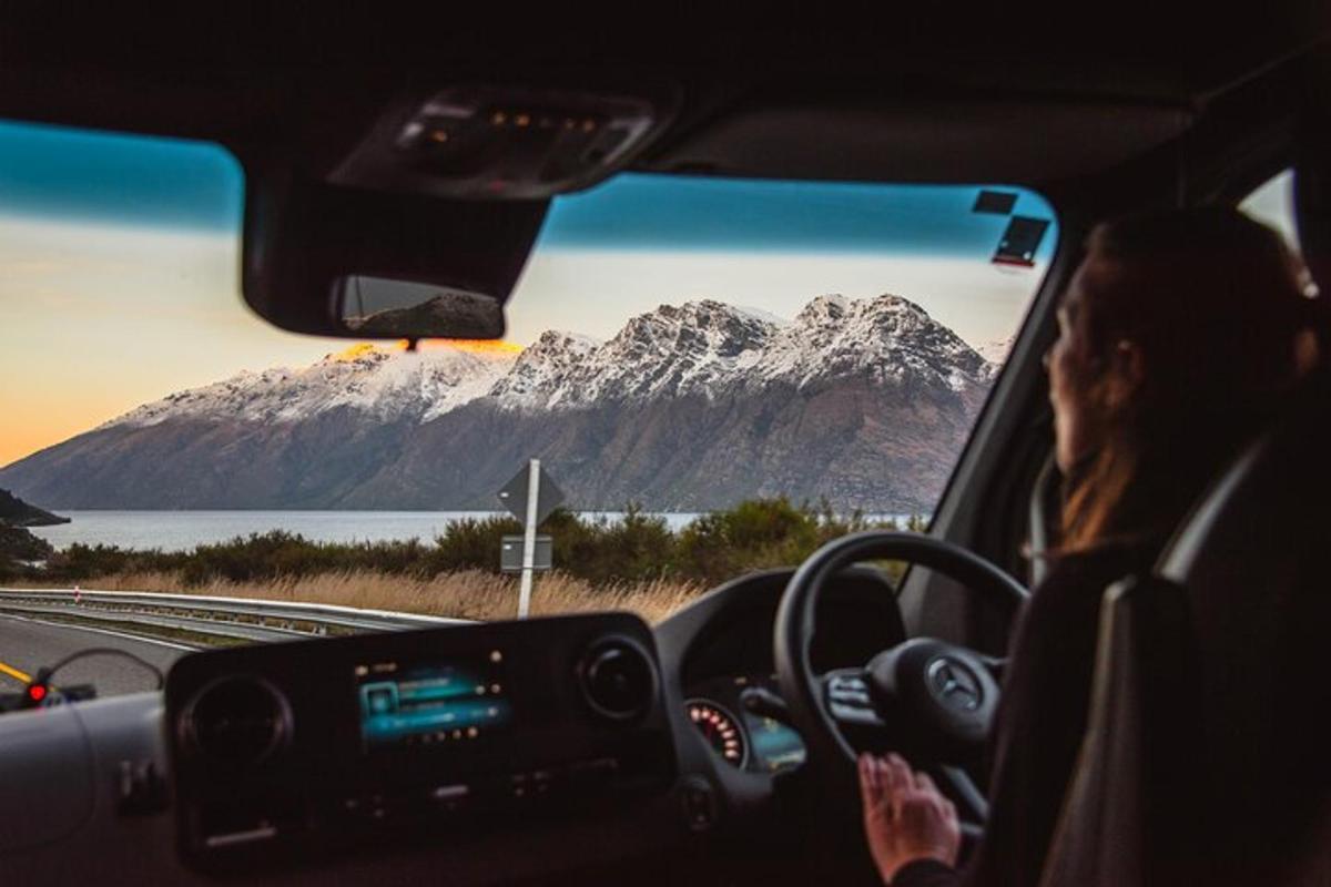 a woman driving a car with a mountain in the background