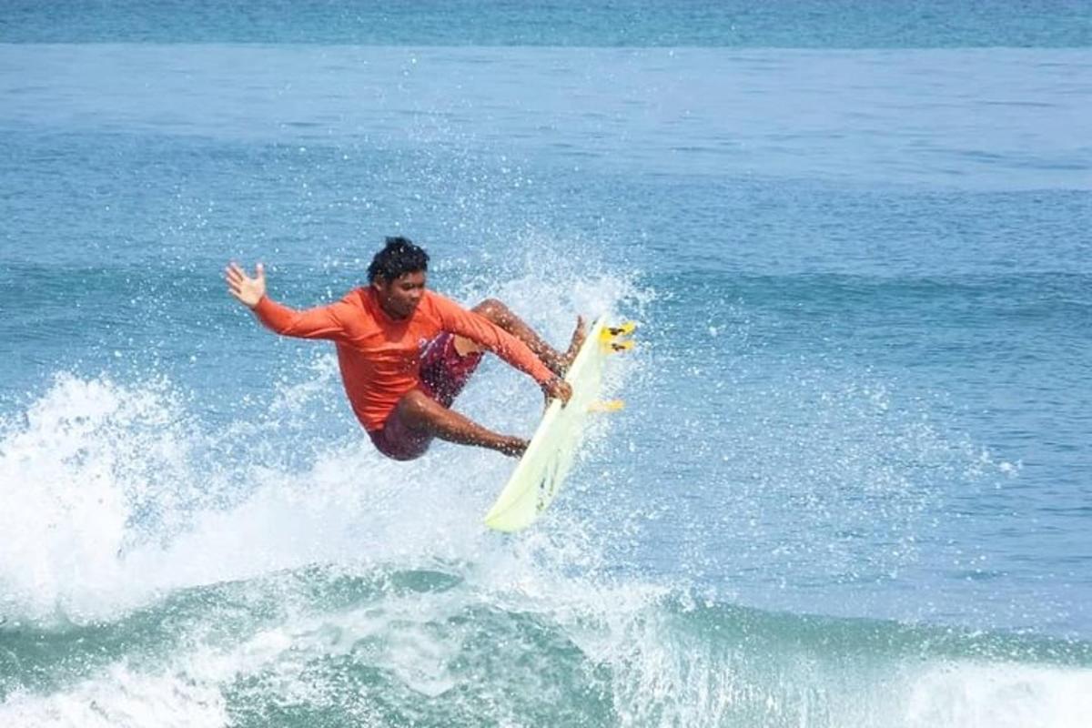 seorang pria mengendarai ombak di papan selancar di lautan