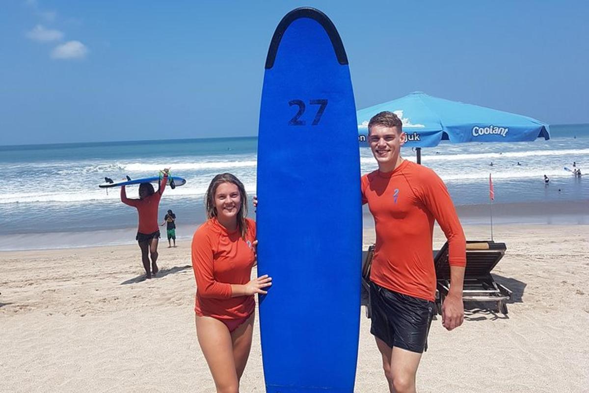 moški in ženska držita modro desko za surfanje na plaži