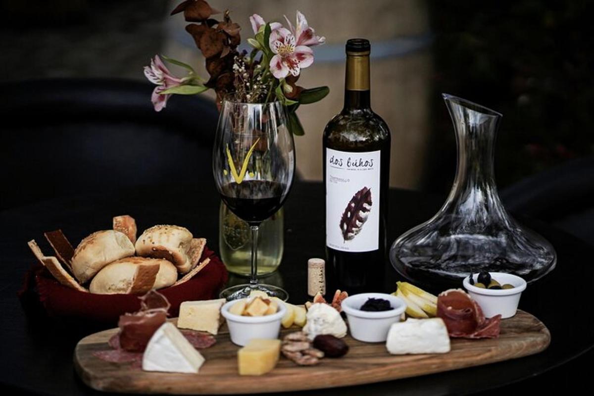 Una mesa con una botella de vino y un plato de queso.