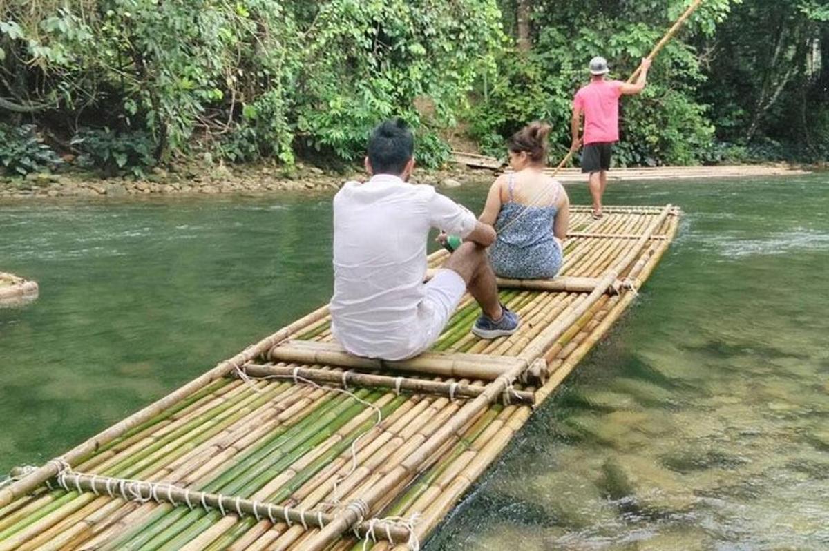 ein Mann und eine Frau sitzen auf einem Bambusfloß in einem Fluss
