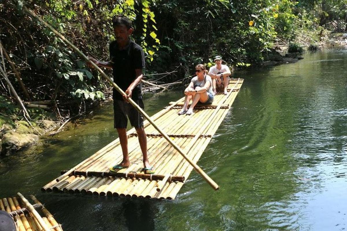 ein Junge steht auf einem Bambusfloß in einem Fluss