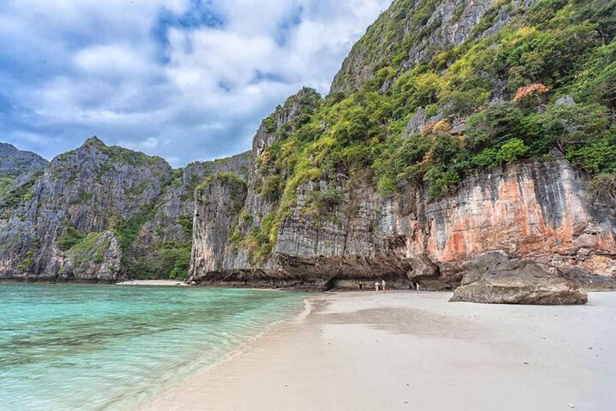 plaża z ludźmi stojącymi na piasku obok góry