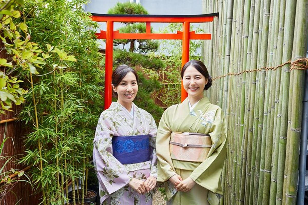 Dos mujeres con kimonos de pie junto a una valla
