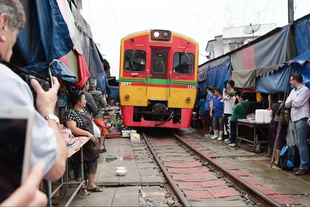 รถไฟสีแดงและสีเหลืองวิ่งไปตามรางข้างฝูงชน