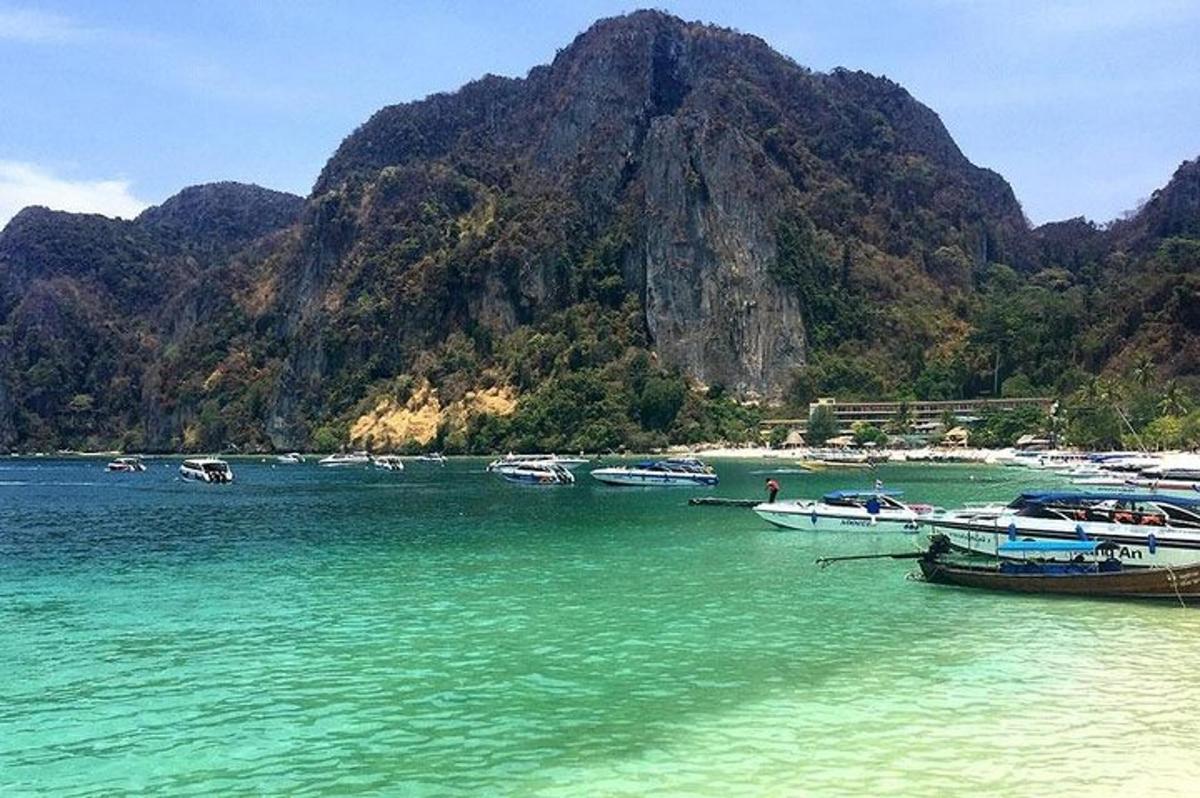 a group of boats in the water near a mountain