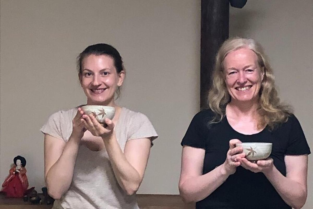 two women smiling while holding cups in their hands