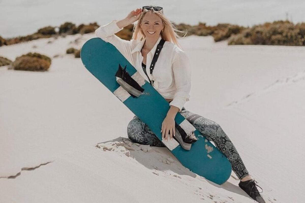 žena sedící ve sněhu a držící snowboard