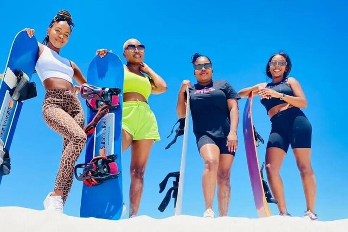 skupina lidí stojících v písku se snowboardy
