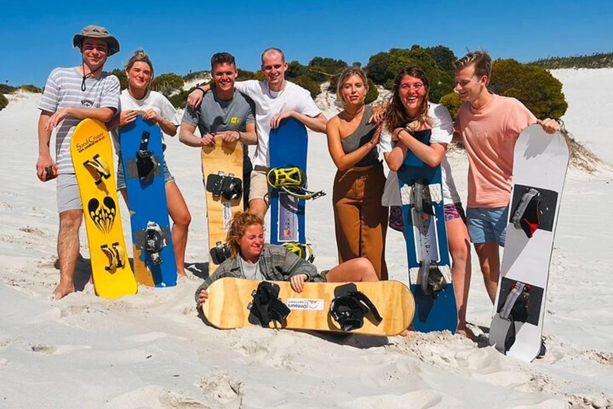 skupina lidí stojících v písku se snowboardy
