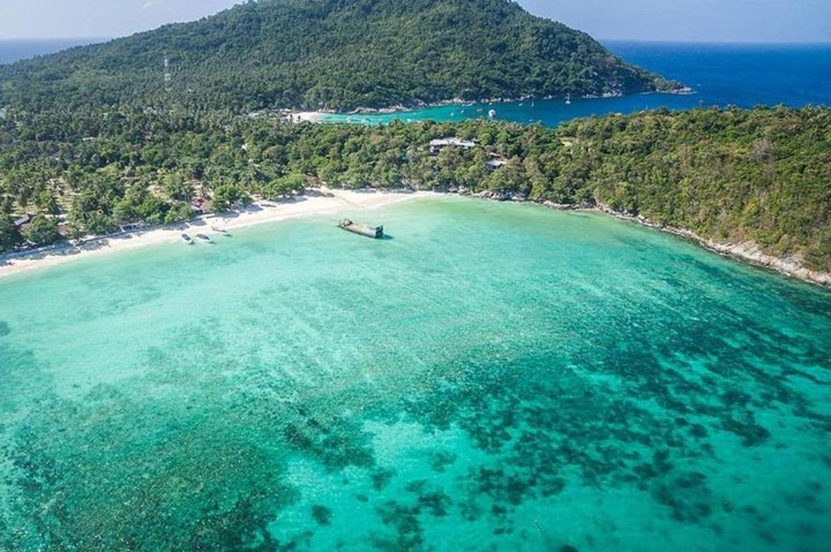 Una vista aérea de una playa con un barco en el agua.
