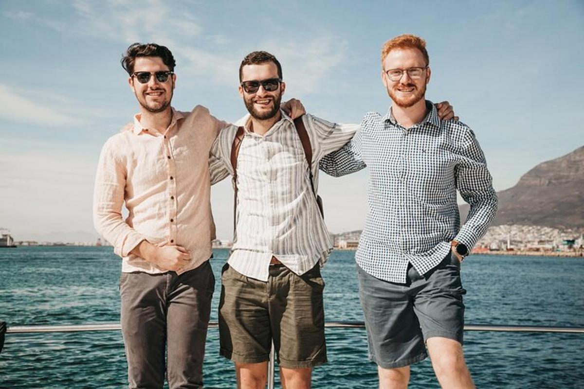 three men standing on a boat near the water