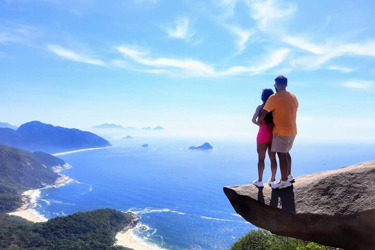 a couple standing on top of a rock overlooking the ocean