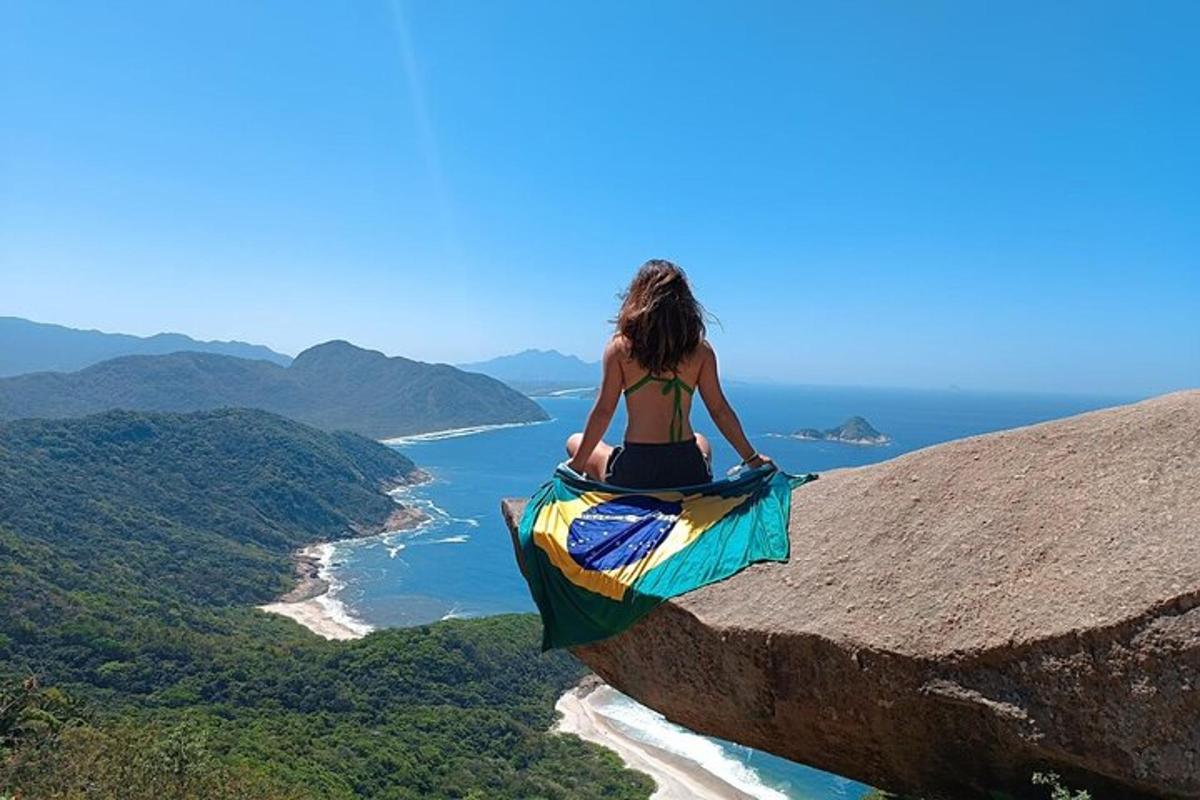 a woman sitting on top of a rock overlooking the ocean