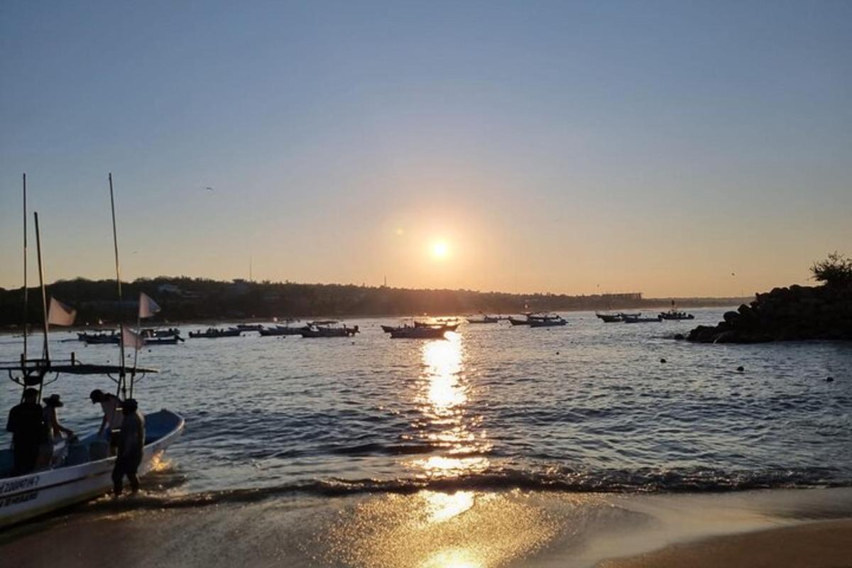 Un grupo de personas de pie en la playa junto a un barco.