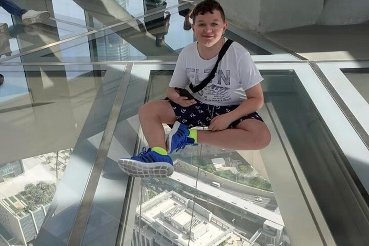 a young boy sitting on the glass floor of a building