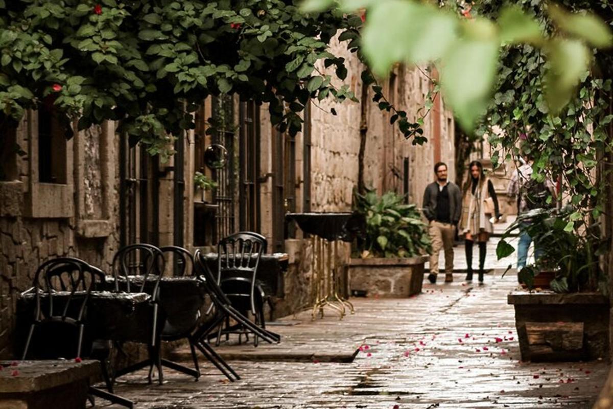 two people walking down an alley with tables and chairs