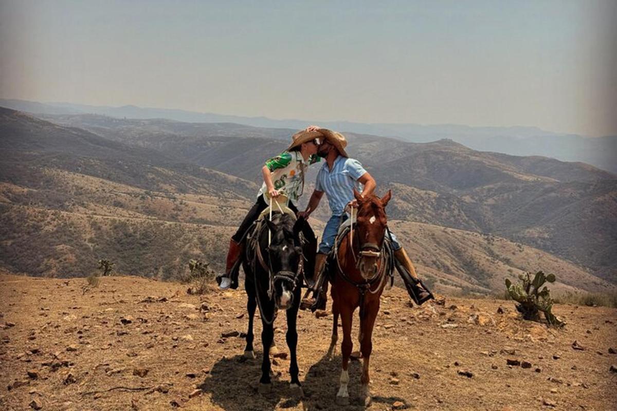 a man and a woman riding a horse on a mountain