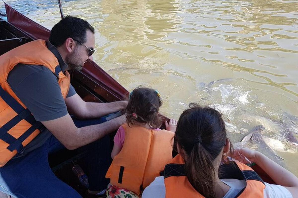 Mees ja kaks tüdrukut paadis delfiini vaatamas