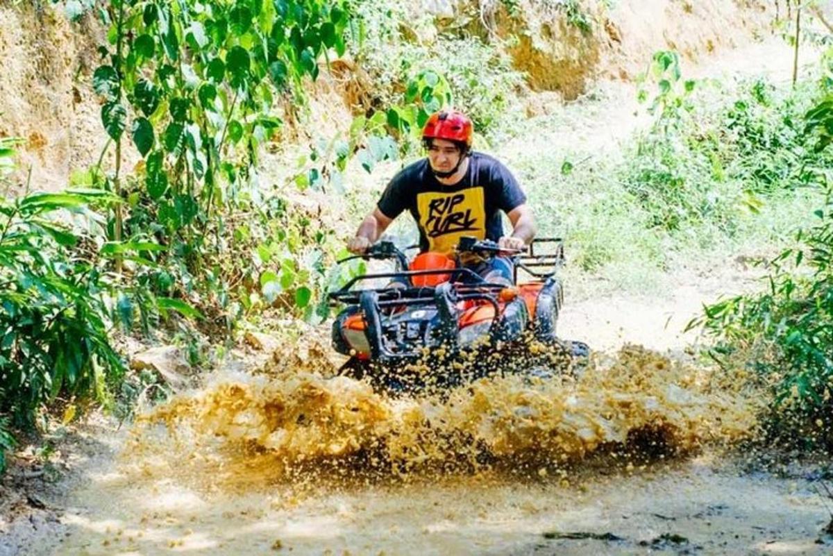 um homem pilotando um quadriciclo por uma trilha lamacenta