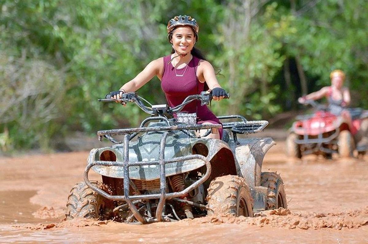 uma mulher andando de quadriciclo na lama