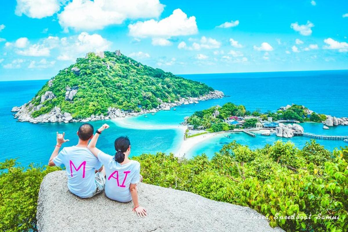 un uomo e una donna seduti su una roccia che guardano un'isola