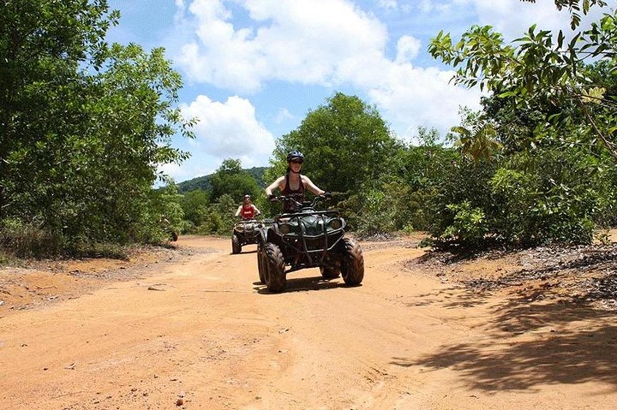 một người đàn ông đang lái xe bốn bánh trên con đường đất