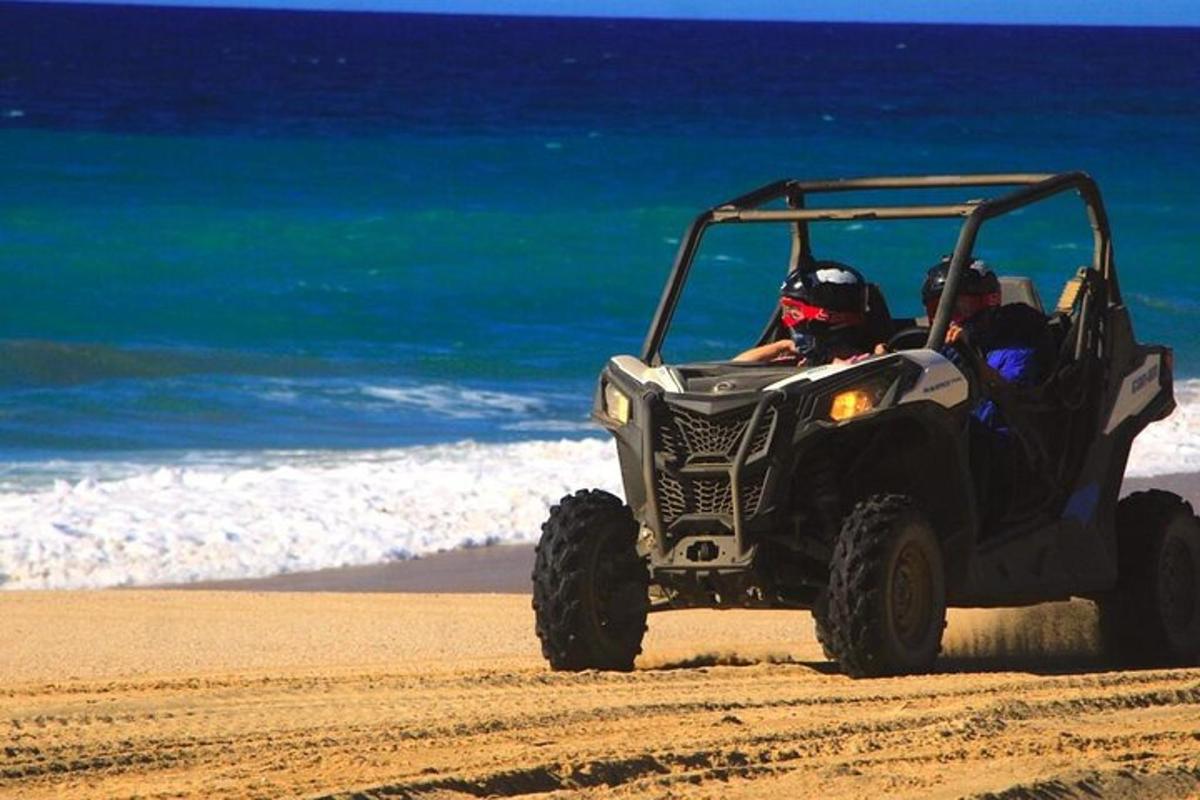 two people riding in a four wheeler on the beach
