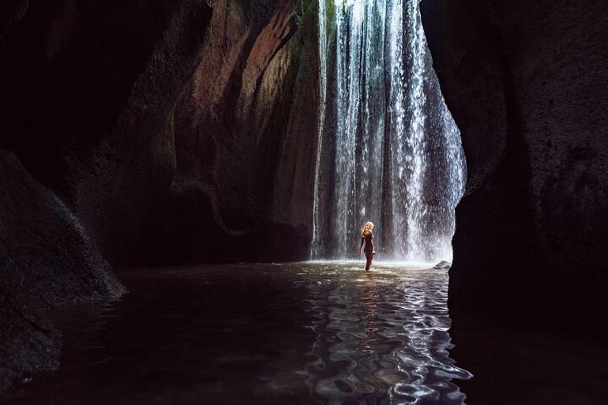 uma pessoa parada na água em frente a uma cachoeira