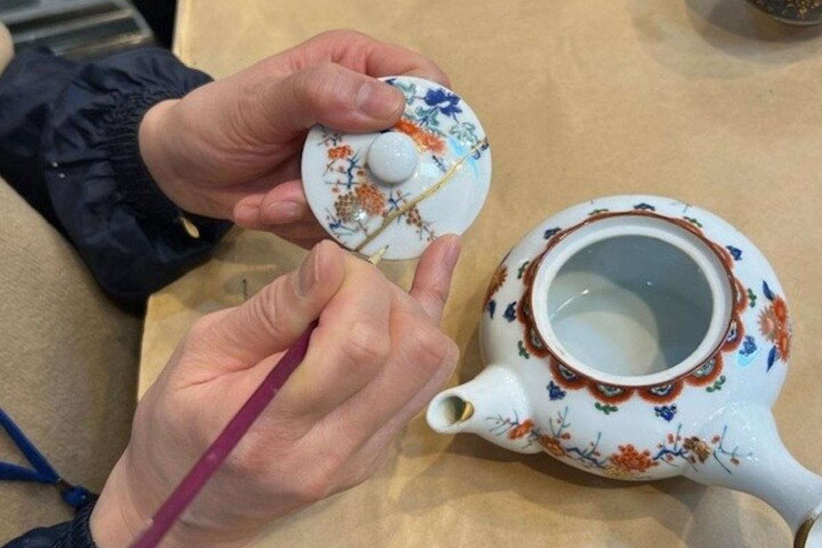en person som holder en tekanne og en kopp kaffe